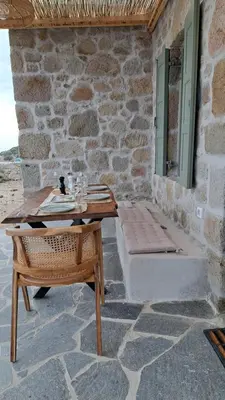 a wooden table and bench on a stone patio at Nisyros Nest in Nikiá