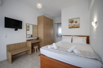 a bedroom with a bed and a desk and a television at Stefanos House Stegna in Archangelos