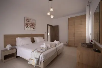 a bedroom with a large white bed with two candles on it at Stefanos House Stegna in Archangelos