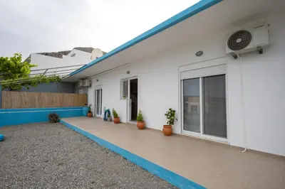 a white house with a patio with potted plants at Stefanos House Stegna in Archangelos