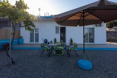 a table and chairs with an umbrella in front of a house at Stefanos House Stegna in Archangelos