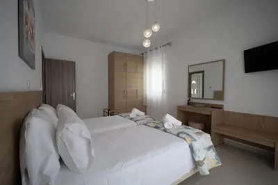 a bedroom with a white bed and a mirror at Stefanos House Stegna in Archangelos
