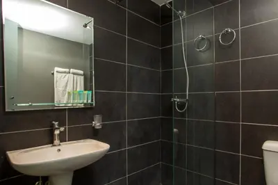 a bathroom with a sink and a mirror and a toilet at Ampelia Hotel in Gennadi