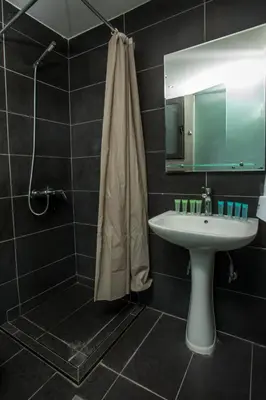 a bathroom with a sink and a shower and a mirror at Ampelia Hotel in Gennadi