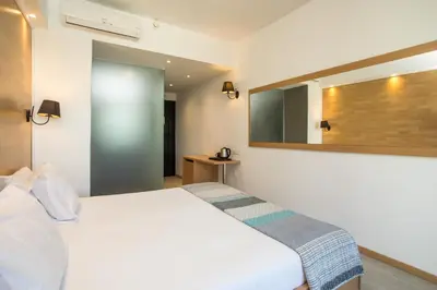 a bedroom with a white bed and a mirror at Ampelia Hotel in Gennadi