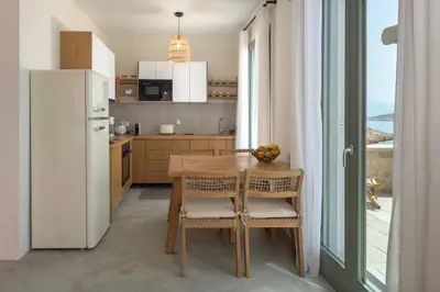 a kitchen with a wooden table and a refrigerator at Onar Residences Chalki in Halki
