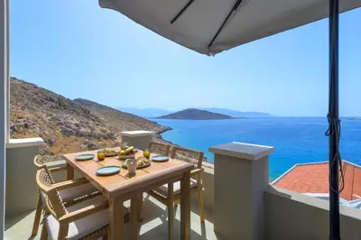 a table on a balcony with a view of the ocean at Onar Residences Chalki in Halki