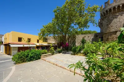 a stone walkway next to a building with a tree at D'Amboise House in Rhodes Town