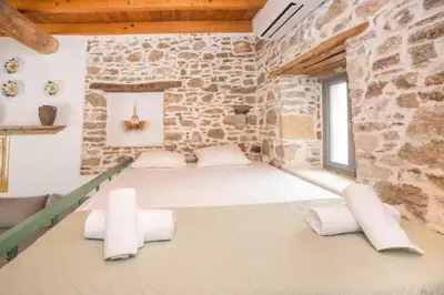 a large room with a stone wall with white pillows at Amarantos-Traditional Village House-Apollona in Apóllona