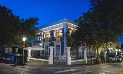a white building with a fence in front of it at Victoria Mansion A Luxurious Neoclassical Experience in Rhodes Town