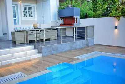 an outdoor kitchen with a grill and a swimming pool at Hillside Horizon Villa in Rhodes Town