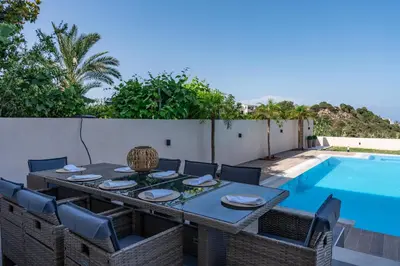 a dining table and chairs next to a swimming pool at Hillside Horizon Villa in Rhodes Town