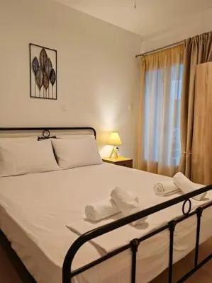 a bedroom with a bed with white sheets and a window at Leo's & Xerxes' place in the Heart of Rhodes in Rhodes Town