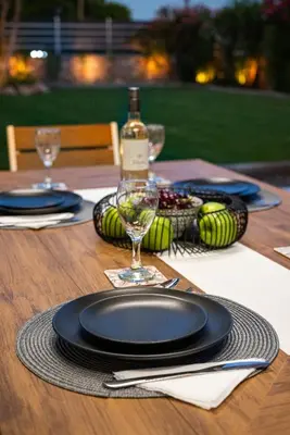 a wooden table with black plates and a bottle of wine at Villa Mariani II - in Lothiarika, newly renovated June 2024, private pool, Lindos 10 min, beach 120m in Lardos