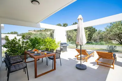 a patio with a table and chairs and an umbrella at Villa Laura in Afantou