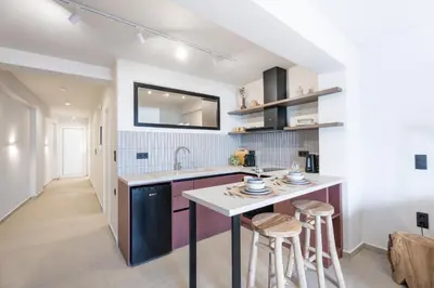 a kitchen with a sink and a counter with stools at Sunny Sands Seaview Apartment in Archangelos