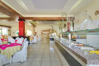 a restaurant with white tables and white chairs and a buffet at Golden Odyssey in Kolimbia