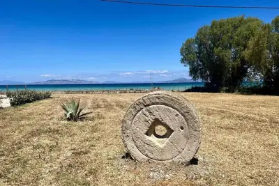 a stone wheel sitting in the middle of a field at Lambou Beach Sunset in Soroni