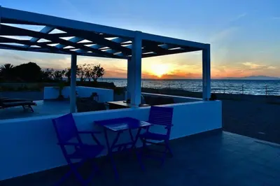 a patio with a table and chairs and the ocean at Lambou Beach Sunset in Soroni