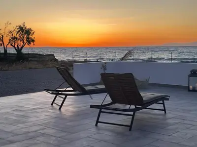 two chairs sitting on a patio with a view of the ocean at Lambou Beach Sunset in Soroni