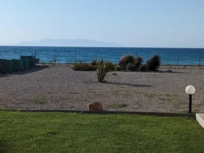 a beach with plants and the ocean in the background at Lambou Beach Sunset in Soroni