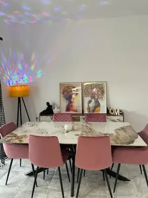 a dining room with a table and pink chairs at BeeHouse in Kalithies