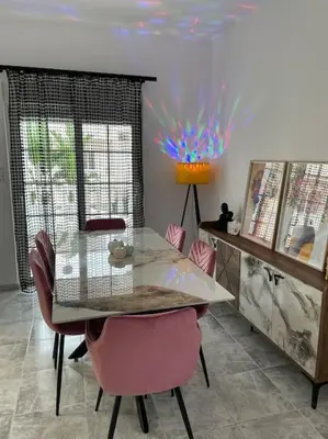 a dining room with a glass table and pink chairs at BeeHouse in Kalithies