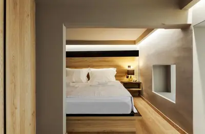 a bedroom with a white bed with a wooden headboard at Chrysma Urban Living in Rhodes Town
