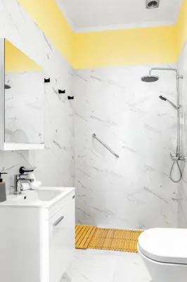 a bathroom with white marble walls and a yellow ceiling at Themis' Urban Residence in Rhodes Town