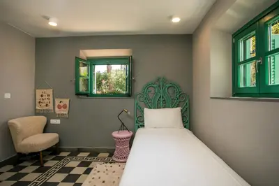 a bedroom with a bed and a chair and windows at Villa Luna Piena in Pefki Rhodes