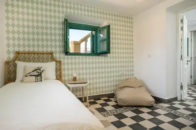 a bedroom with a bed and a mirror and a checkered floor at Villa Luna Piena in Pefki Rhodes
