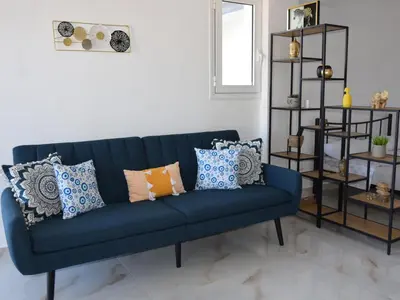 a blue couch with pillows in a living room at Gemini Apartment in Afantou