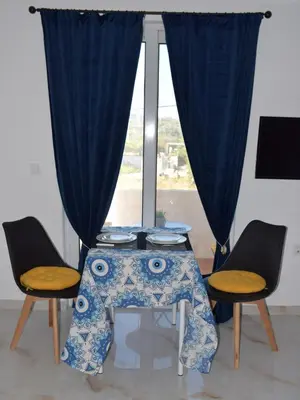 a table with two chairs and a blue curtain at Gemini Apartment in Afantou