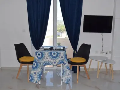 a table and chairs with a table and a screen at Gemini Apartment in Afantou