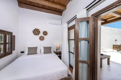 a bedroom with a white bed and a glass door at Elia Suites - Old Town in Rhodes Town