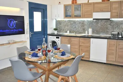 a kitchen with a glass table with chairs and a tv at Alexandra's Sea Front Villa in Pefki Rhodes