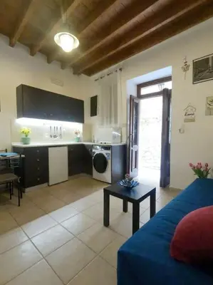 a living room with a blue couch and a kitchen at Tiny Clock House in Rhodes Town