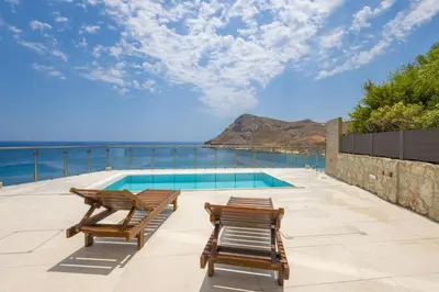 a patio with two chairs and a swimming pool at Villa Pava-sea view brand new villa in Archangelos