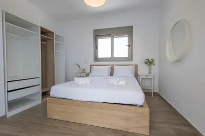 a white bedroom with a white bed and a television at Villa Pava-sea view brand new villa in Archangelos