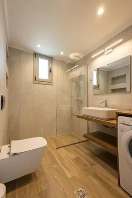 a bathroom with a toilet and a sink and a washing machine at Villa Pava-sea view brand new villa in Archangelos