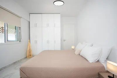 a white bedroom with a large bed with white pillows at Gio Center Apartment in Rhodes Town