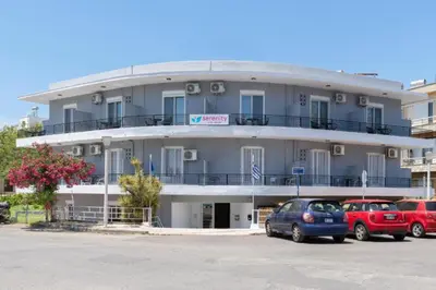 a large building with cars parked in a parking lot at Amethyst Rooms in Rhodes Town