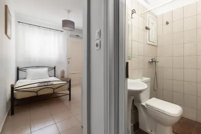 a bathroom with a bed and a toilet and a sink at Amethyst Rooms in Rhodes Town