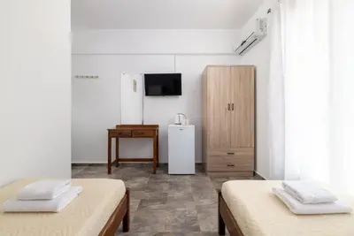 a white room with two beds and a television at Amethyst Rooms in Rhodes Town