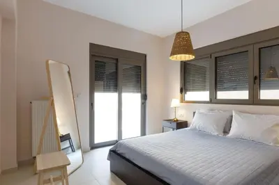 a bedroom with a bed and a lamp and windows at J&G Rhodes city flat in Rhodes Town