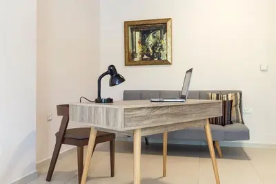 a desk with a laptop computer on it next to a couch at J&G Rhodes city flat in Rhodes Town