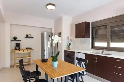 a kitchen with a wooden table and chairs and a kitchen with a refrigerator at J&G Rhodes city flat in Rhodes Town