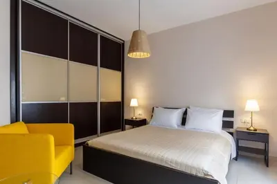 a bedroom with a bed and a yellow chair at J&G Rhodes city flat in Rhodes Town