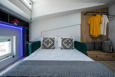 a bedroom with a bed and a yellow shirt hanging on a wall at My Little Tiny House in Rhodes Town