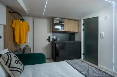 a room with a bed and a yellow shirt on a wall at My Little Tiny House in Rhodes Town